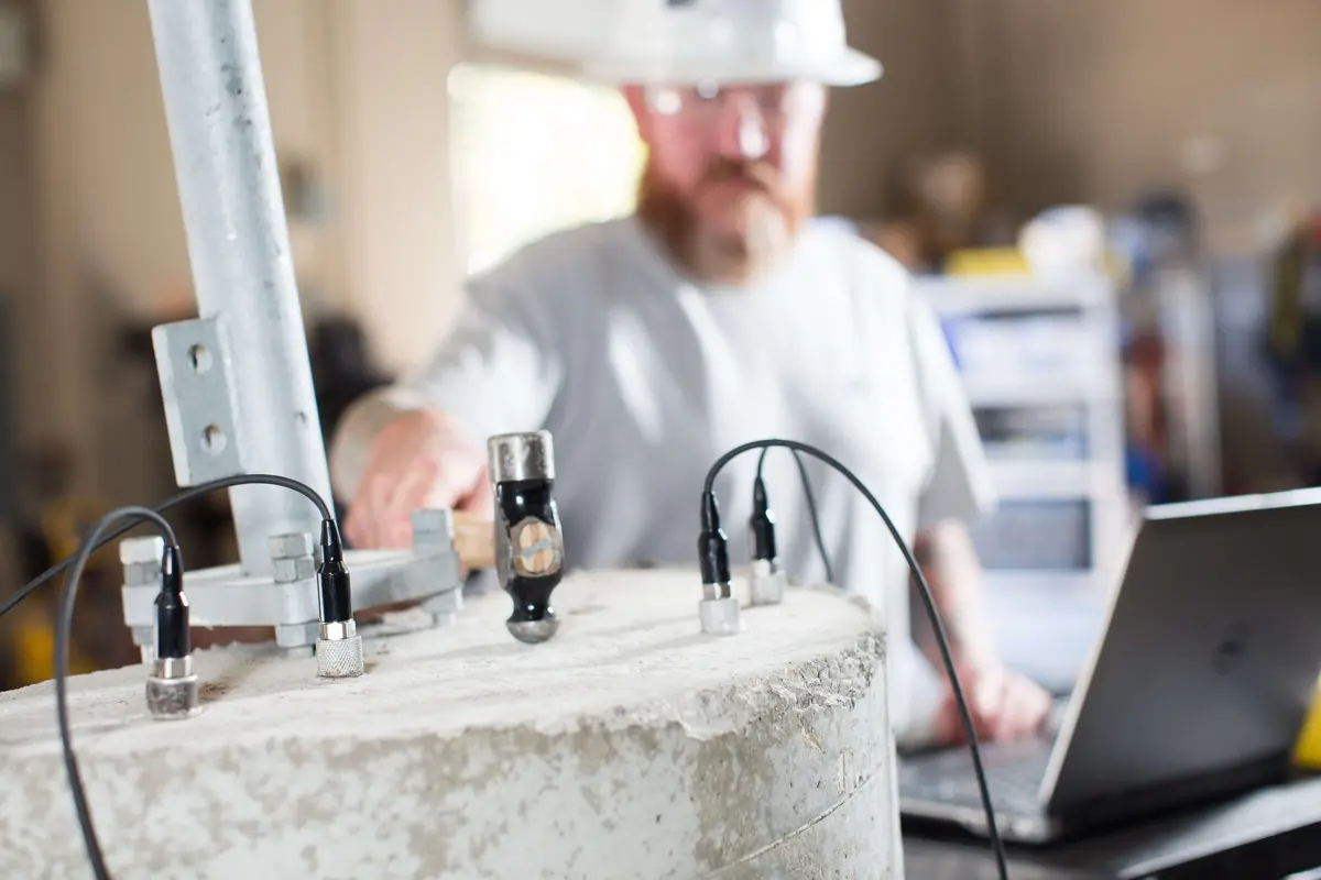 An engineer running sensors on a concrete specimen with a laptop