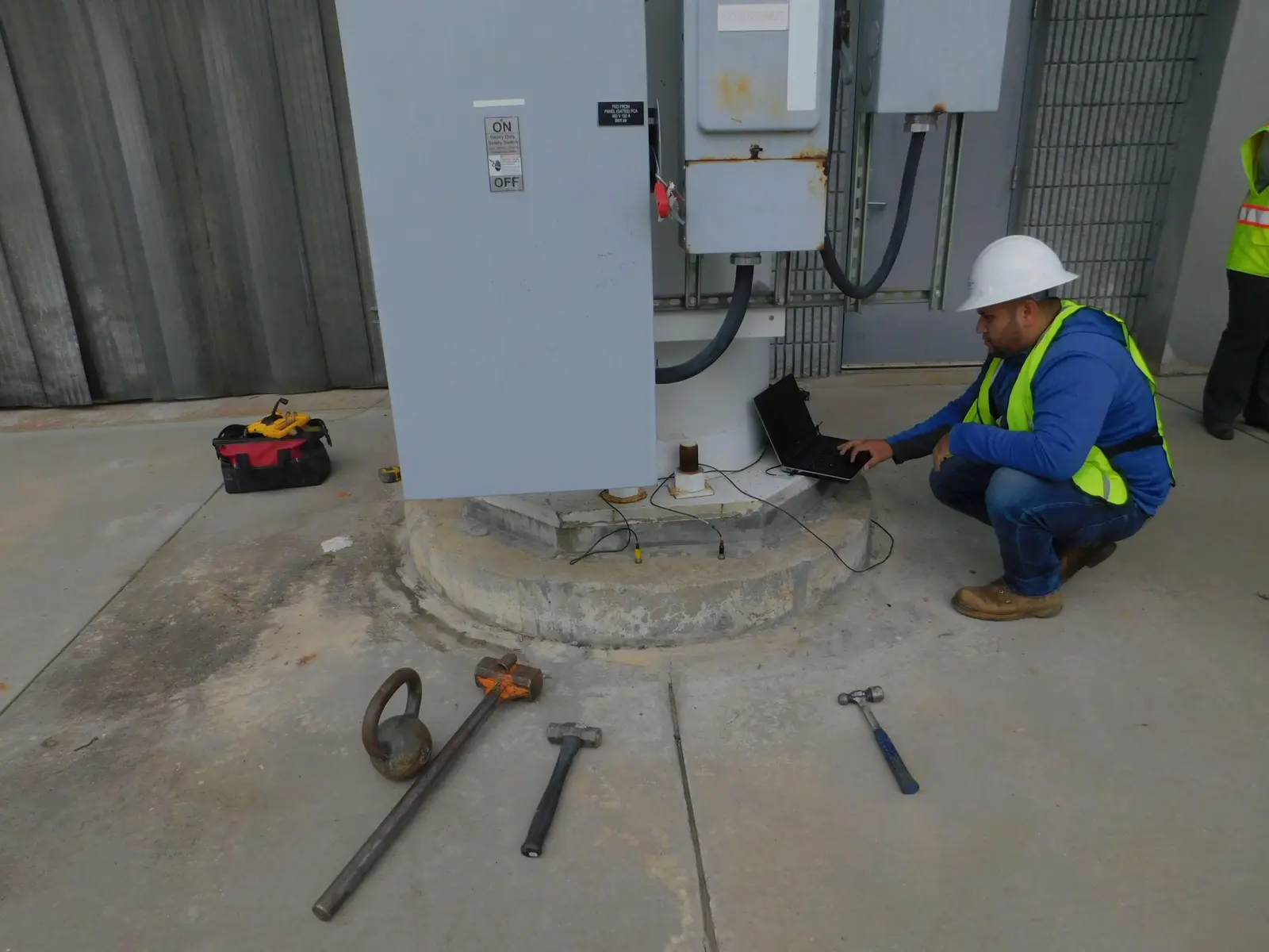 An AAE engineer testing at the base of an equipment cabinet in a tower compound