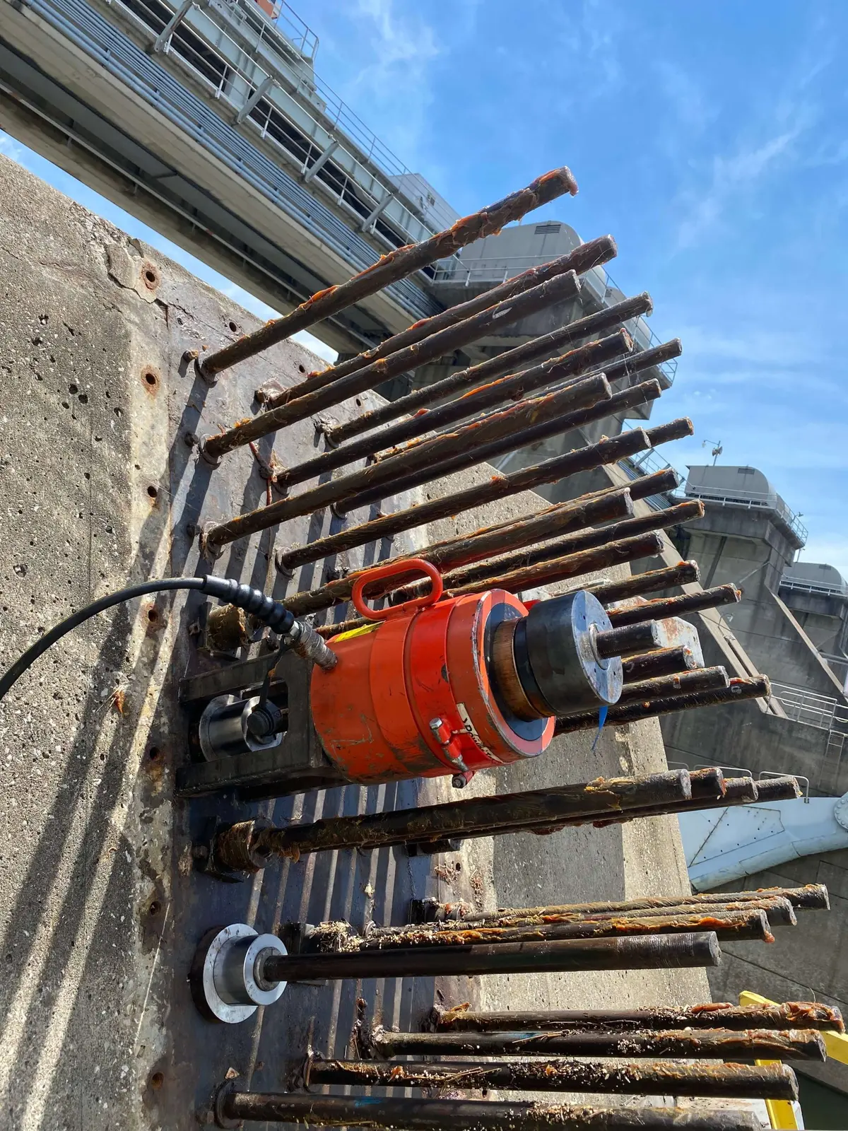 A hydraulic tensioner fitted to anchor rods on a concrete structure